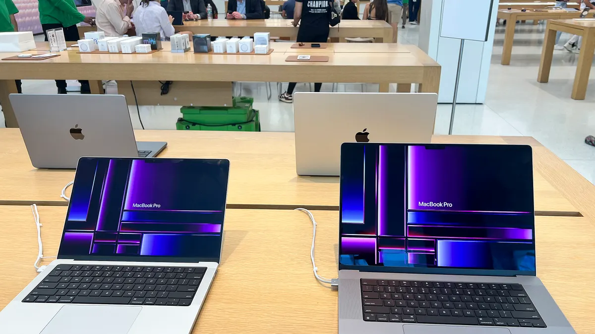 Laptops on display on a beige table in a store.
