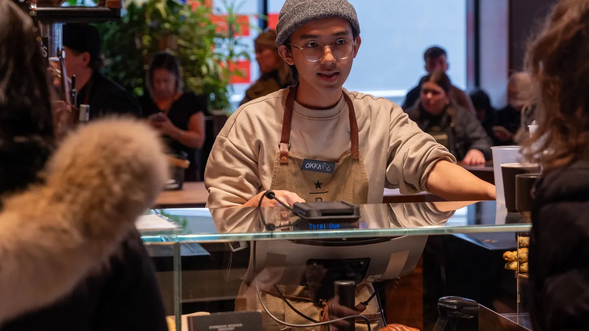 A man takes orders at a Starbucks counter.