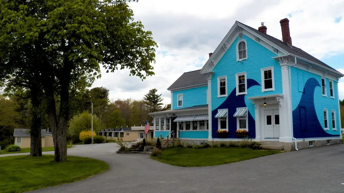 The Coast Village Inn features a teal exterior with a dark blue wave pattern.