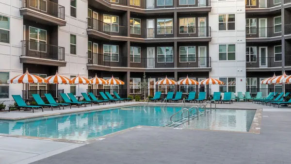 A pool with an apartment community in the background.