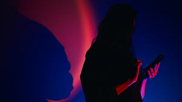 Woman silhouette using smartphone with neon light and shadow.