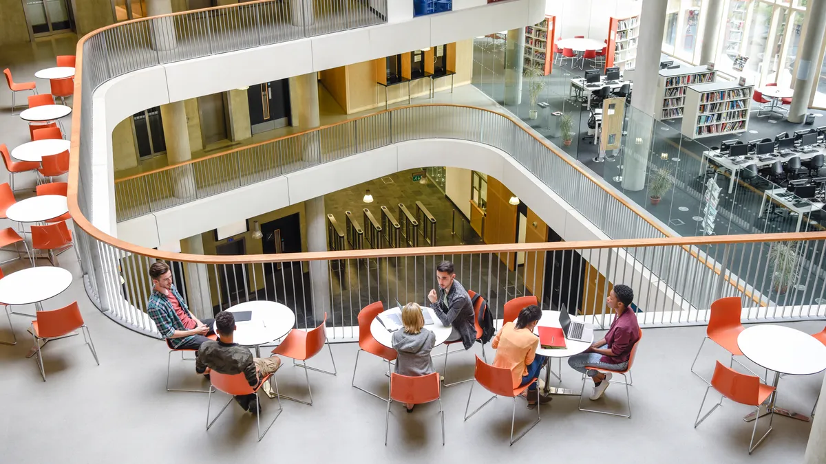 Furniture in open plan building with modern staircase and college students meeting friends