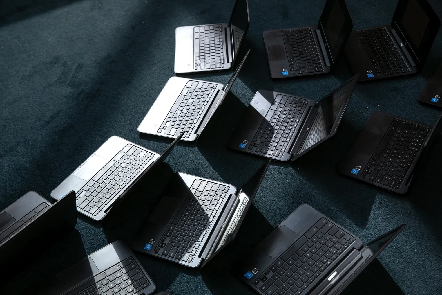 A group of Chromebooks lie open on the floor after being cleaned.