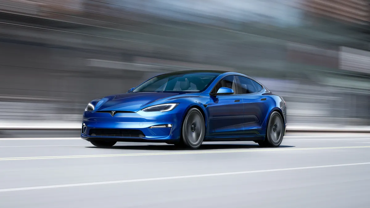 A blue Tesla Model S sedan on the highway.