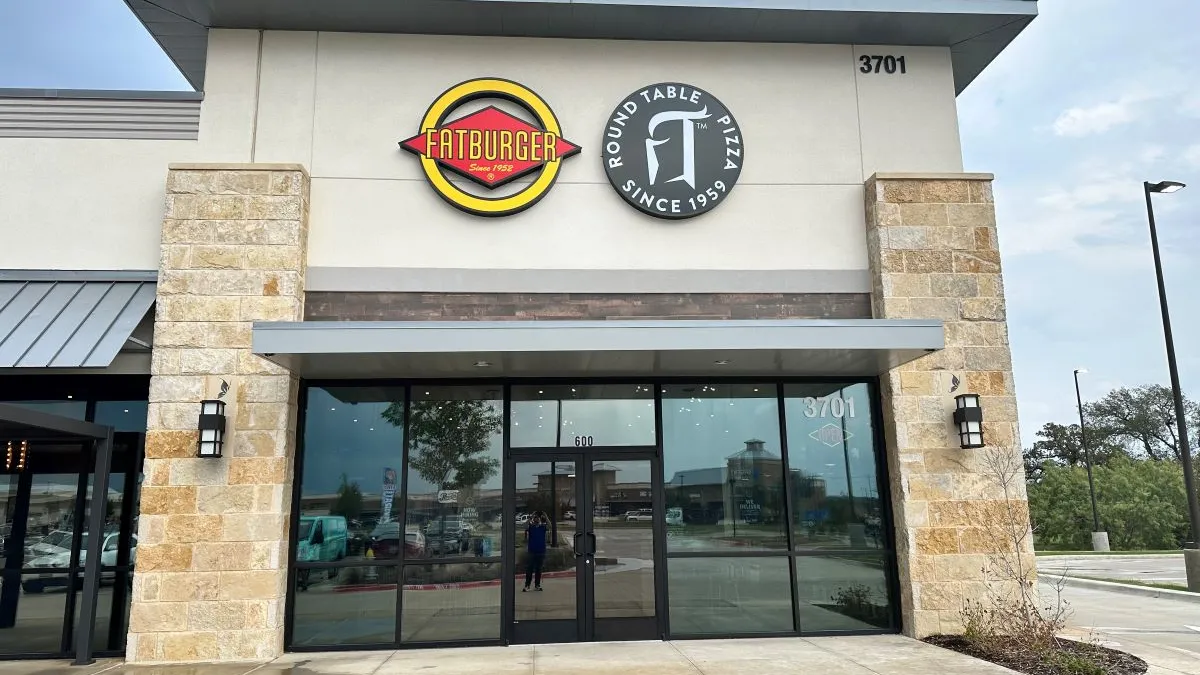 An image of a beige building wiht both Fatburger and Round Table Pizza signage