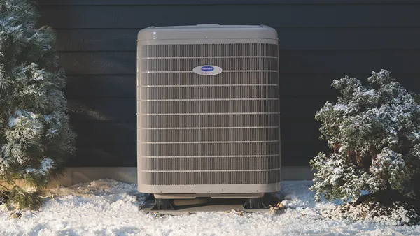Carrier's cold climate heat pump outside of a snowy residential home.