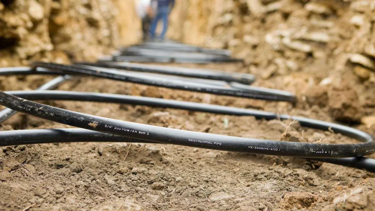 Workers laying geothermal coils in an underground trench