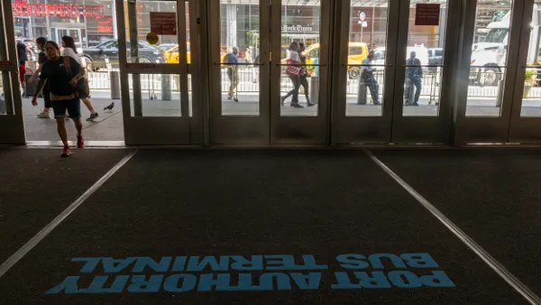 View of dark interior with a woman entering from the street through a glass door.