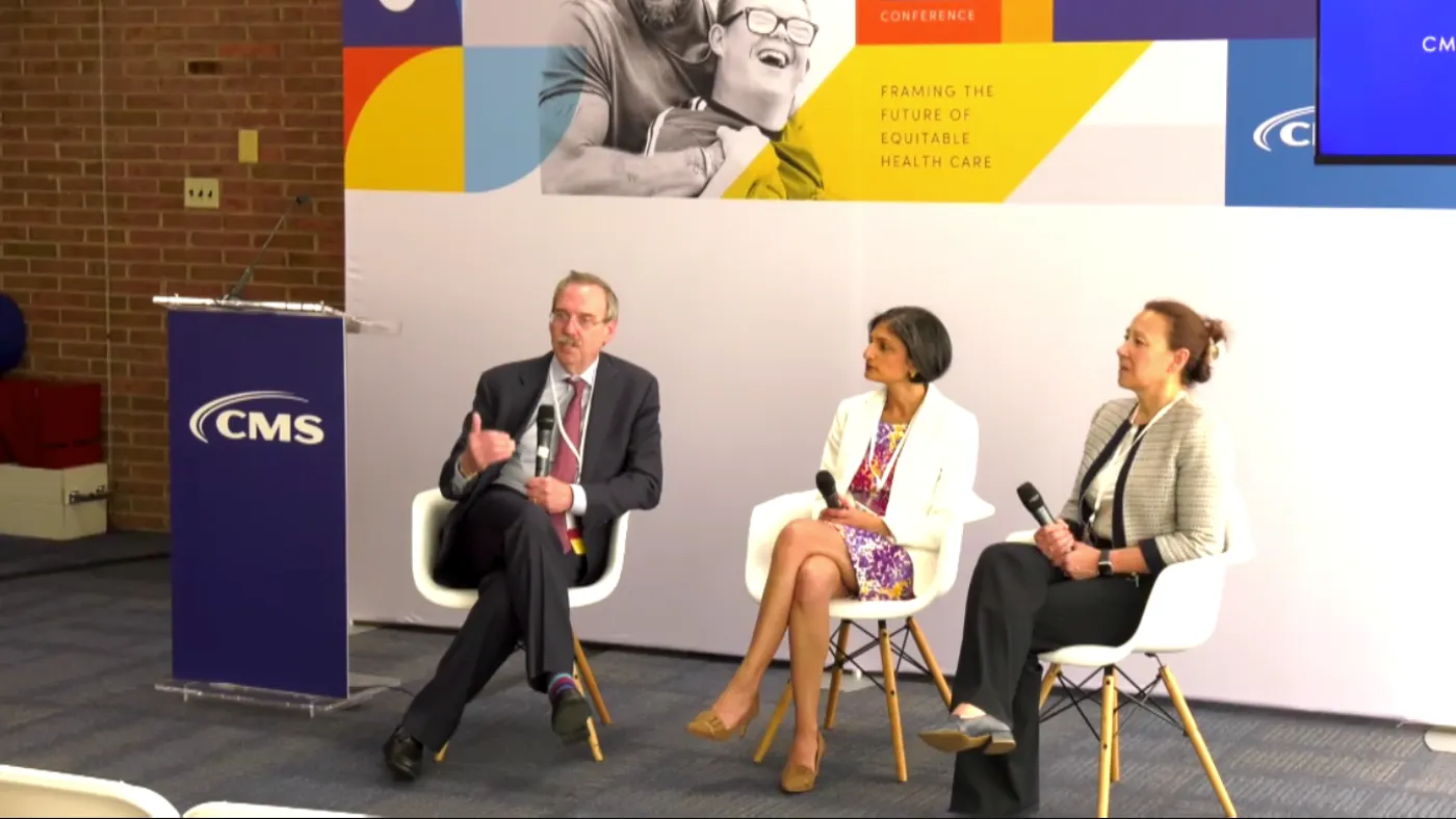 Lee Fleisher, Liz Fowler and Meena Seshamani talk on a panel during the CMS health equity conference in front of a white background.
