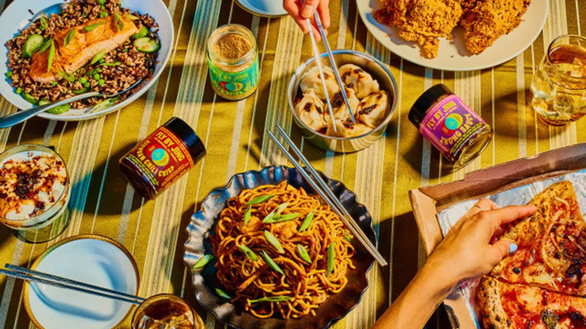 Table with brightly colored jars, hands holding chopsticks and bowls of food