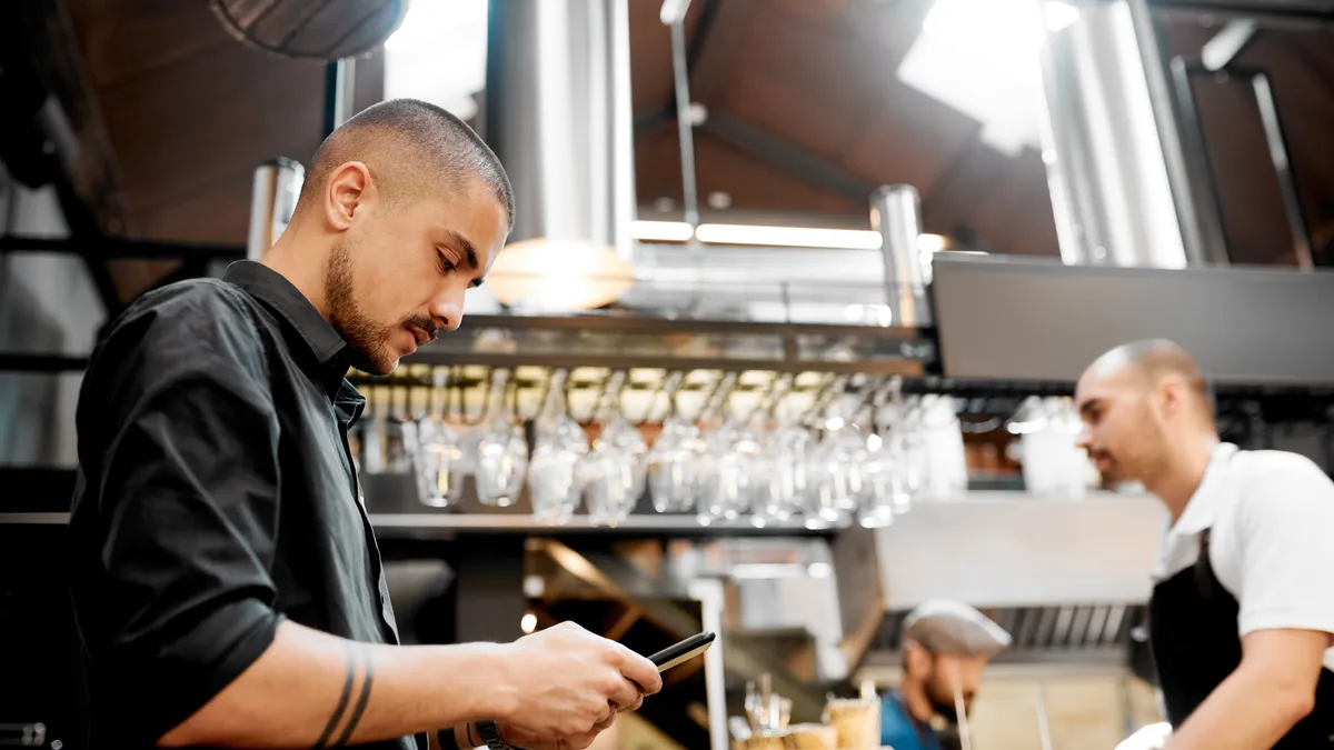 Young man using mobile while working at a cafe