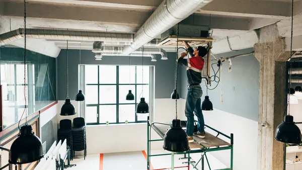 A worker upgrades lighting in an office.
