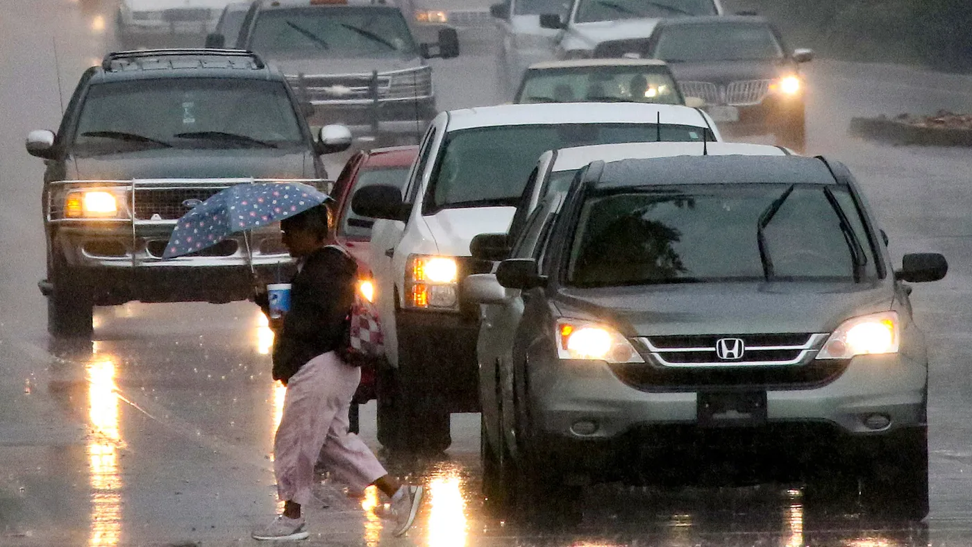 Cars and pedestrians navigate a rainy downtown street in Tucson, Arizona.