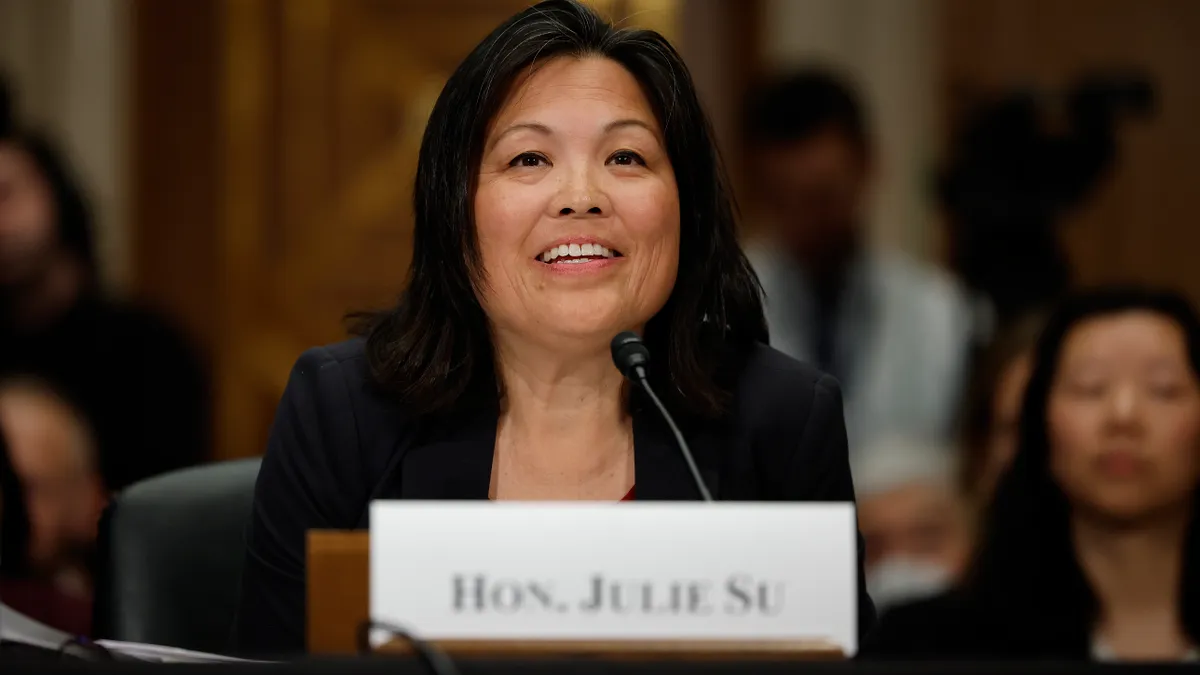 A close-up shot of Deputy Labor Secretary Julie Su as she testifies before Congress; Su is smiling gently