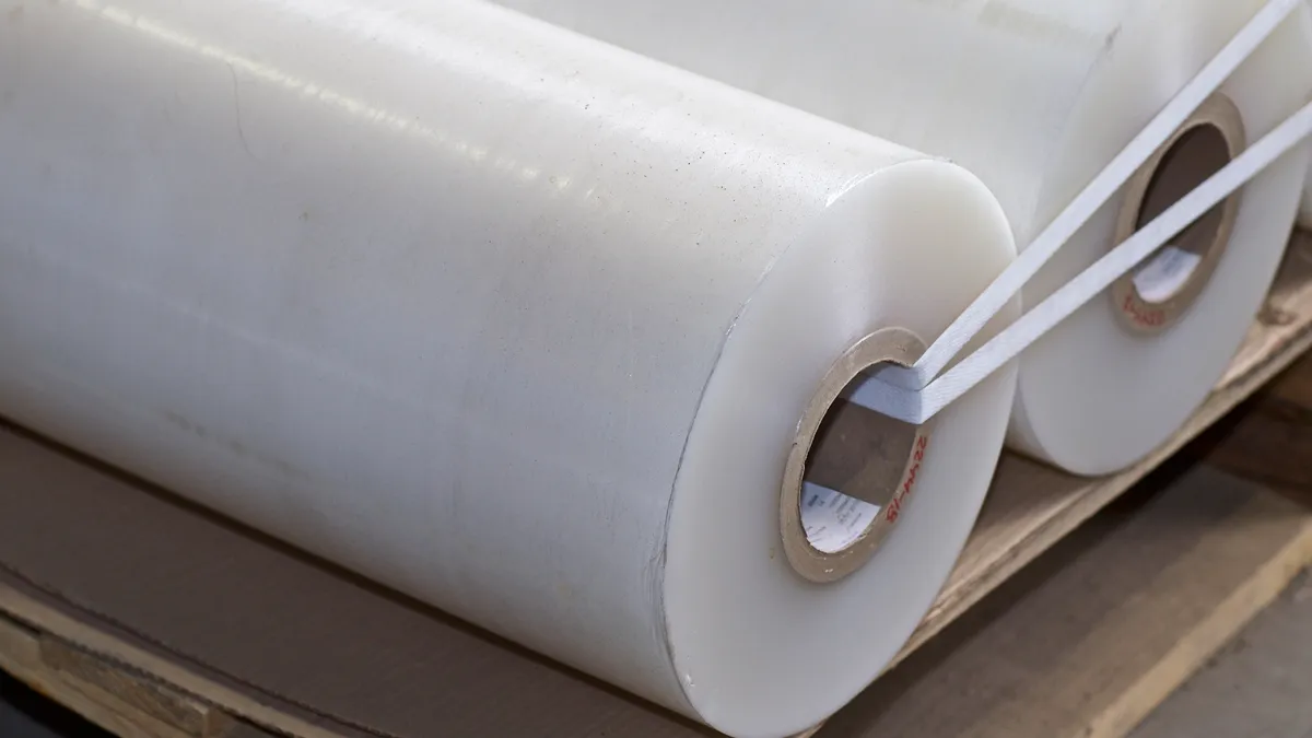 Two rolls of white polymer film laying on cardboard.