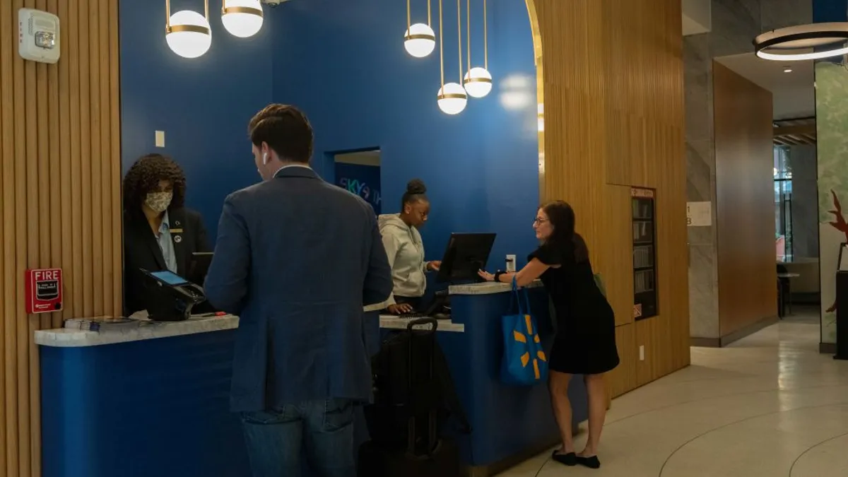 Hotel guests check in at a front desk.