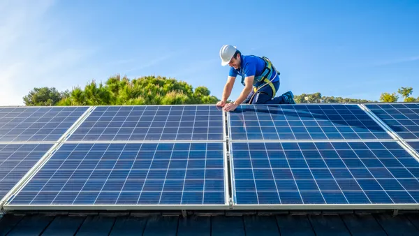 Solar panel installer installing solar panels on roof of modern house.