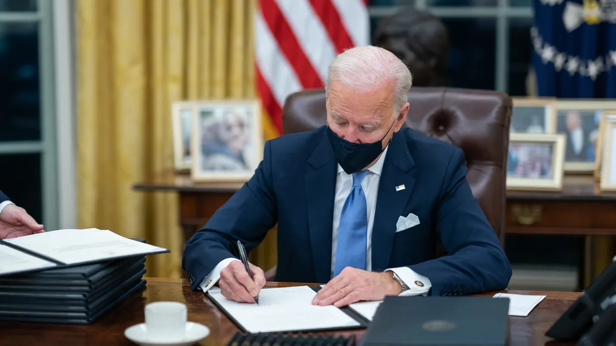 President Joe Biden signs one of the 17 Executive Orders he signed on Inauguration Day Wednesday, Jan. 20, 2021, in the Oval Office of the White House.