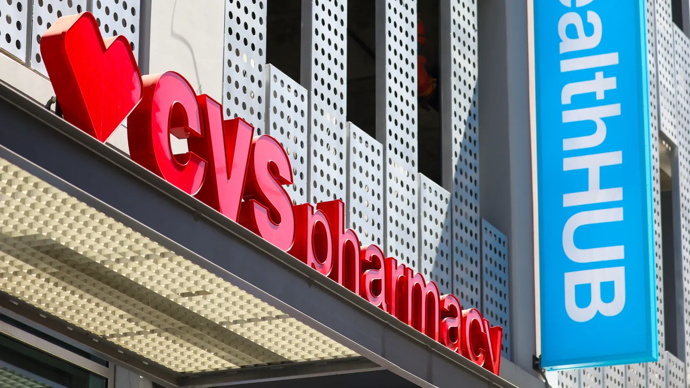 A view from below of the CVS sign on the center of a building, with a vertical blue HealthHub sign to its right.