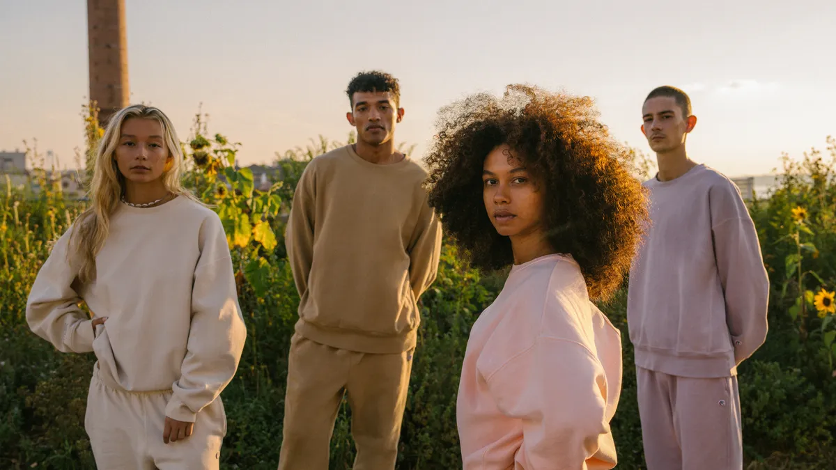 Models stand outside wearing a Champion collection of crewnecks and joggers.