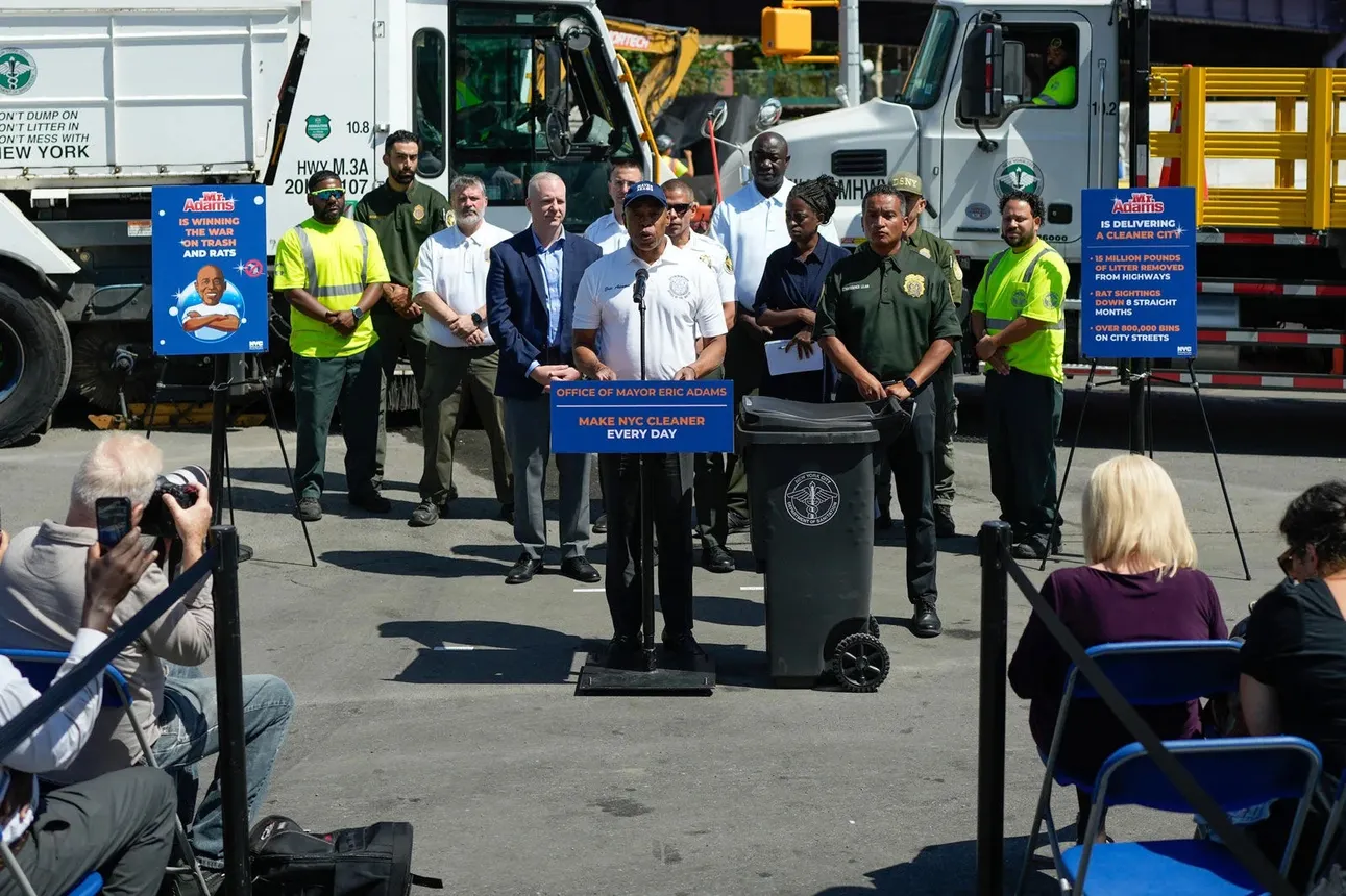 A group of people stand at a press conference, with Mayor Eric Adams in the center
