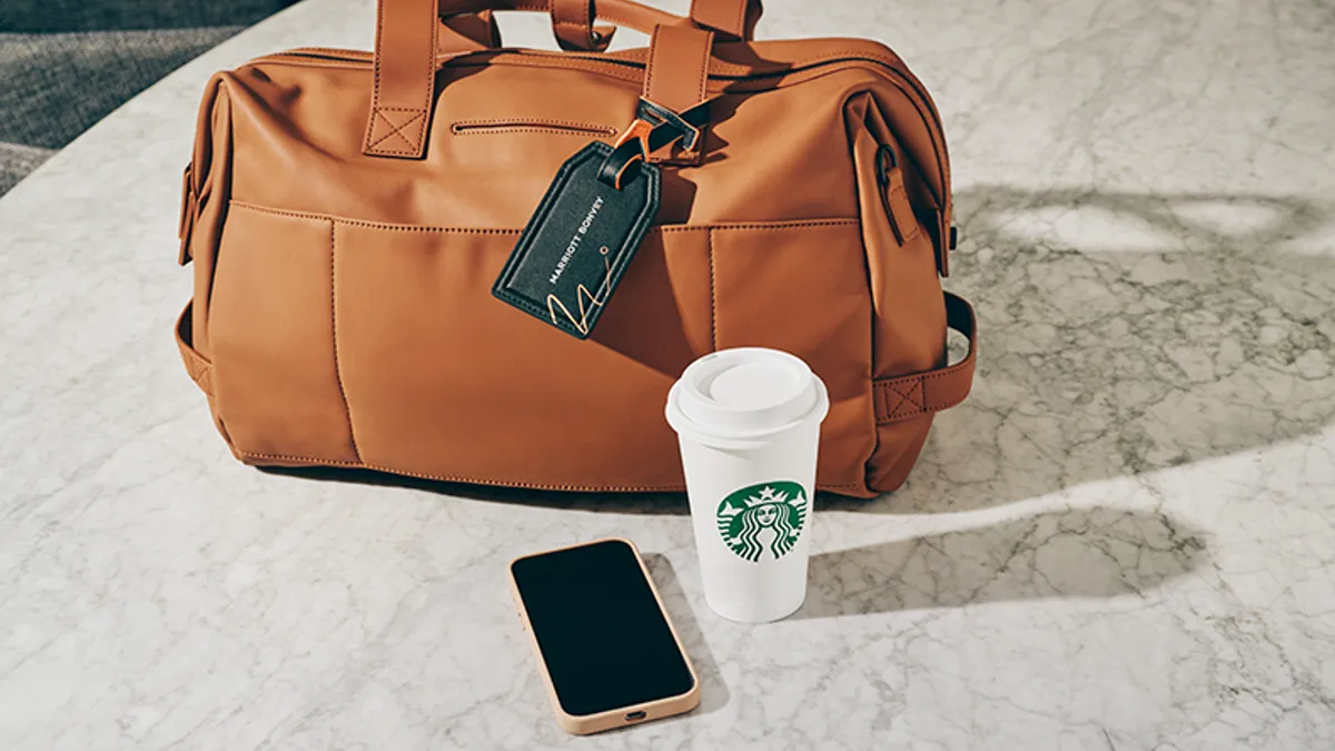 A starbucks cup next to a suitcase.