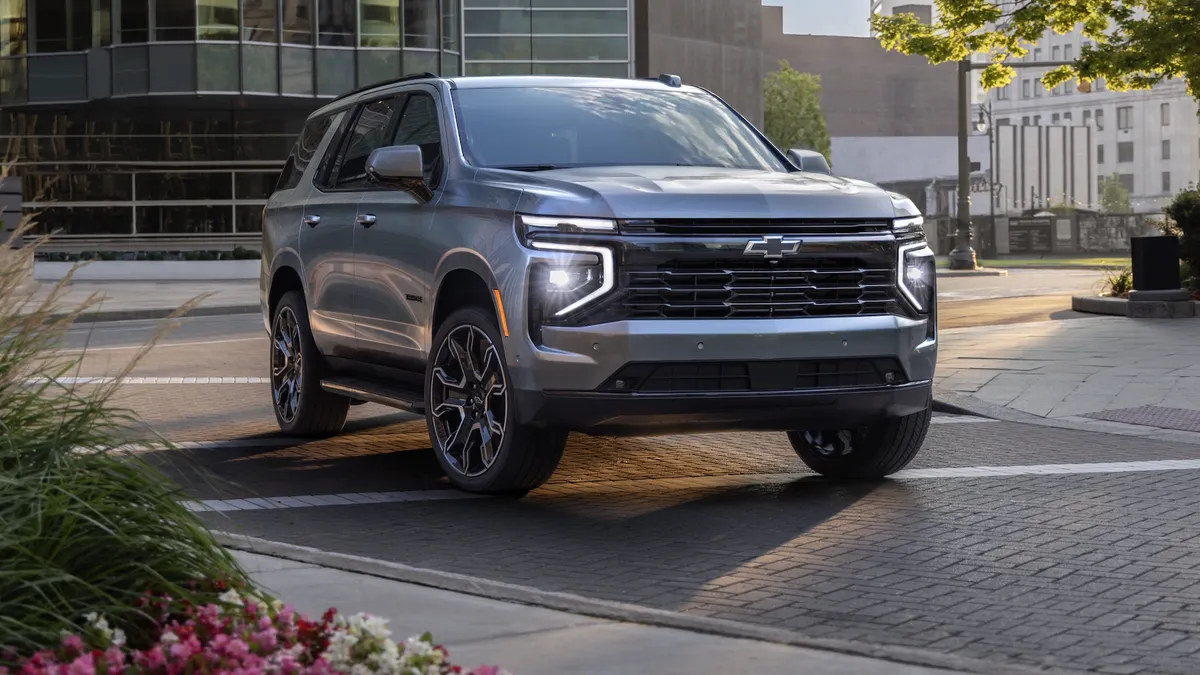 A 2026 Chevrolet Tahoe RST parked outdoors in a urban setting with buildings in the background.