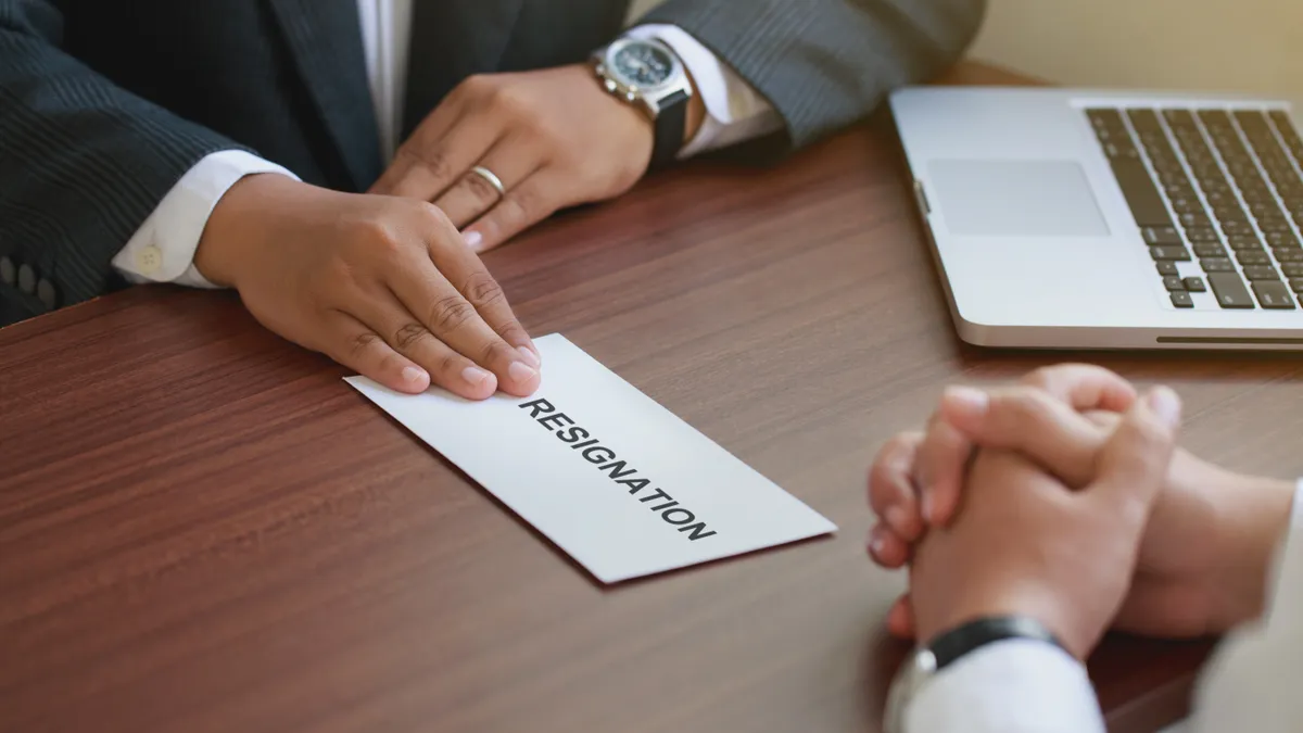 Hand of employer receiving a resignation letter from an employee.