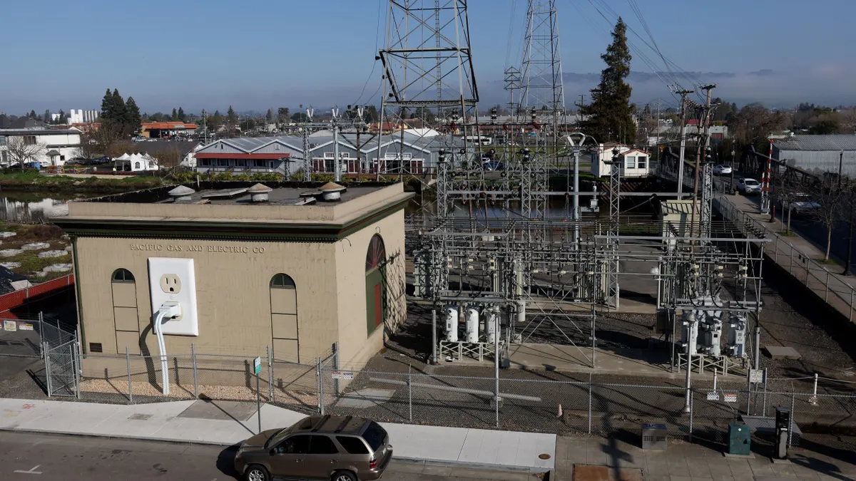 A view of a Pacific Gas & Electric (PG&E) electrical substation with a model power plug on the side of the building.