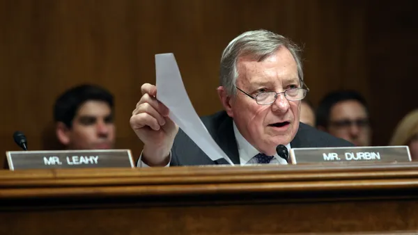 Senator sitting in chamber holds up paper