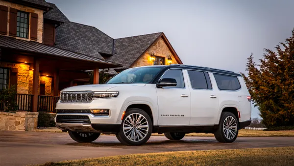 A white 2024 2024 Jeep Grand Wagoneer L parked in front of a house.