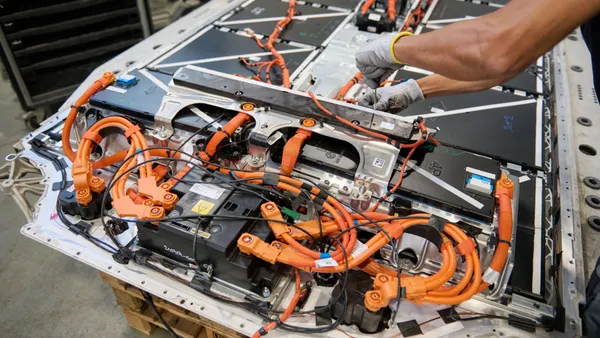 A worker disassembles a high-voltage battery removed from a BMW vehicle.