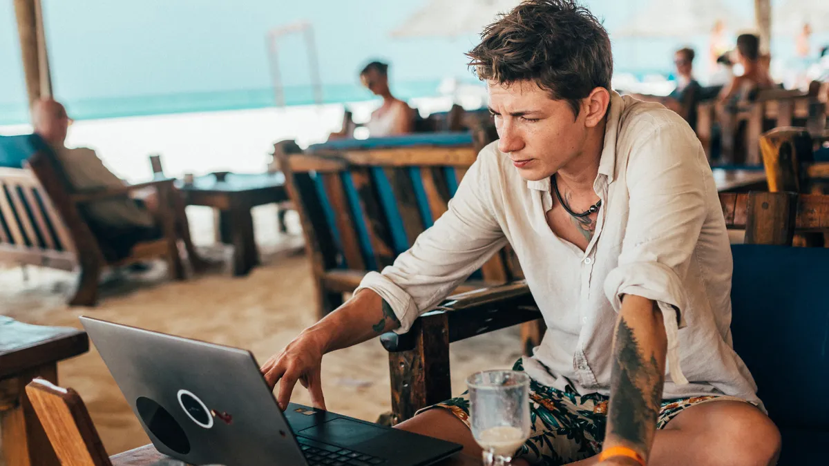 A tattooed man works on a laptop in Zanzibar