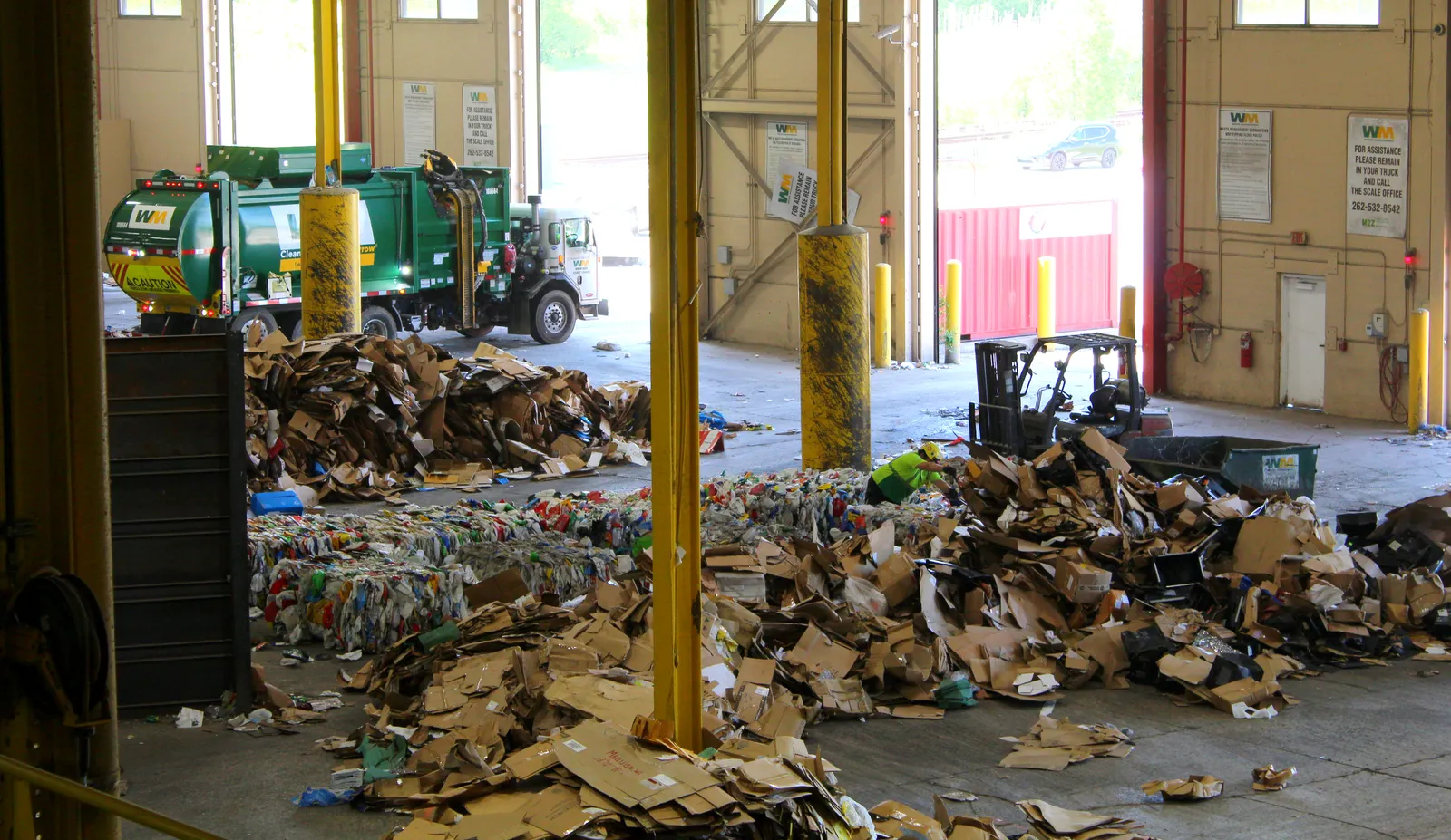 The tipping floor at a recycling facility with a WM truck unoading materials.