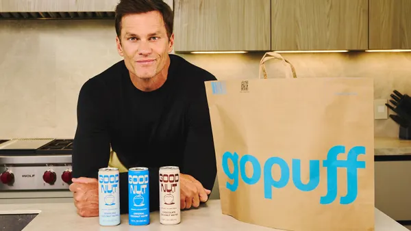 Tom Brady is next to cans of Gopuff and a Gopuff-branded bag.
