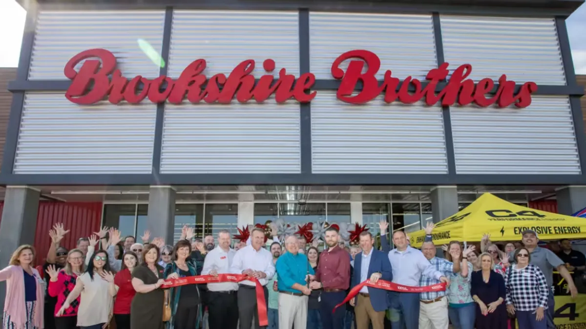 People outside a grocery store celebrating its grand opening.
