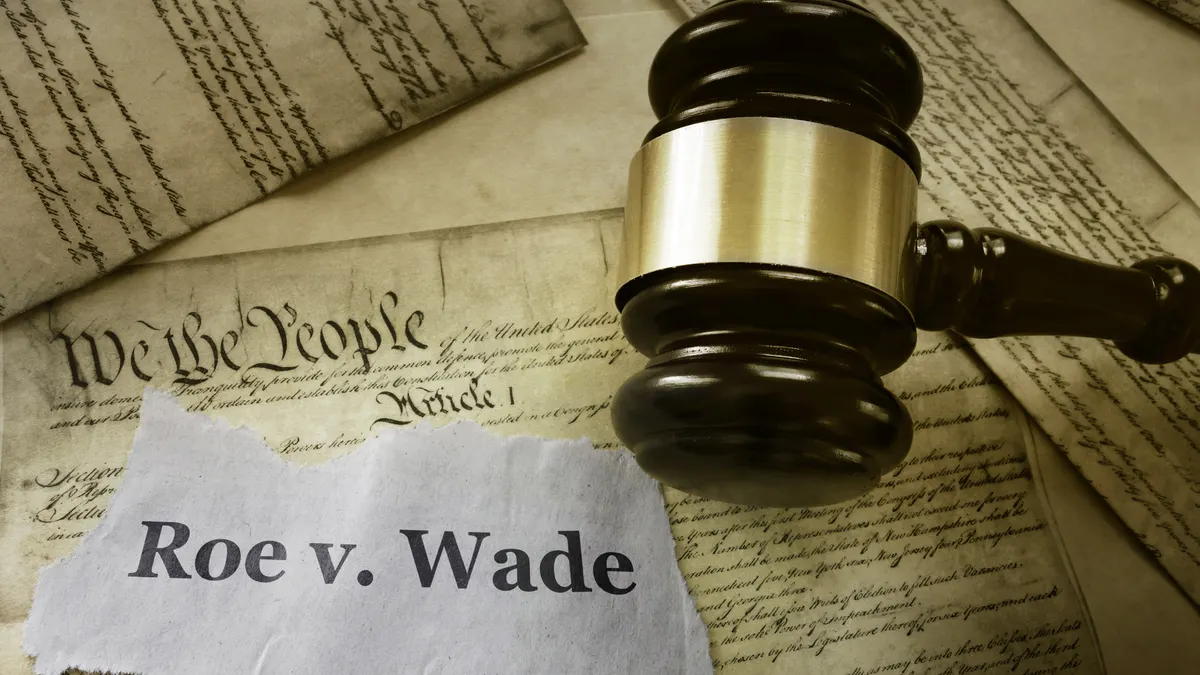 A Roe v Wade news headline with a gavel on a copy of the United States Constitution