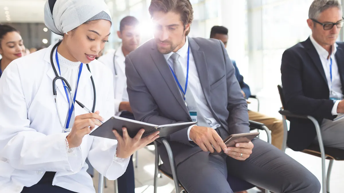 Front view of female mixed race doctor discussing her notes with Caucasian businessman in conference room at office