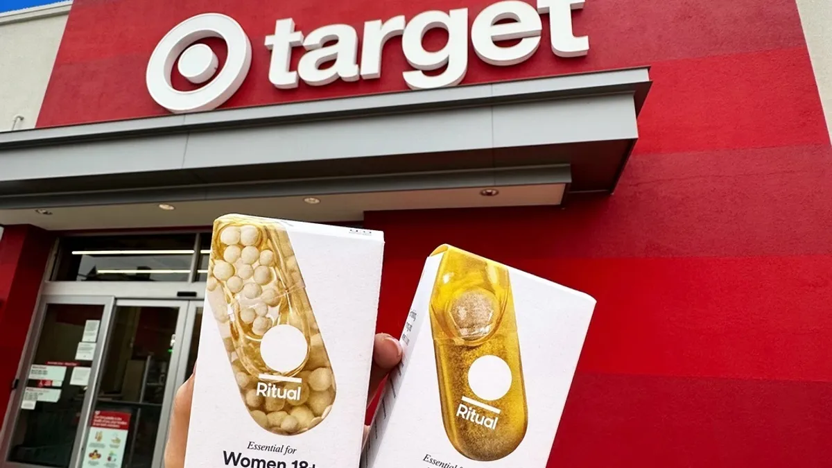 A hand holding yellow vitamin bottles in front of a Target store sign