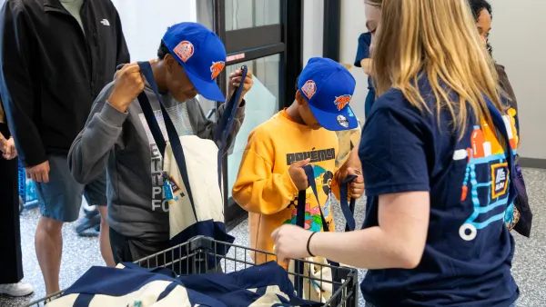 Two kids looking inside Aldi tote bags they were handed by an employee on opening day