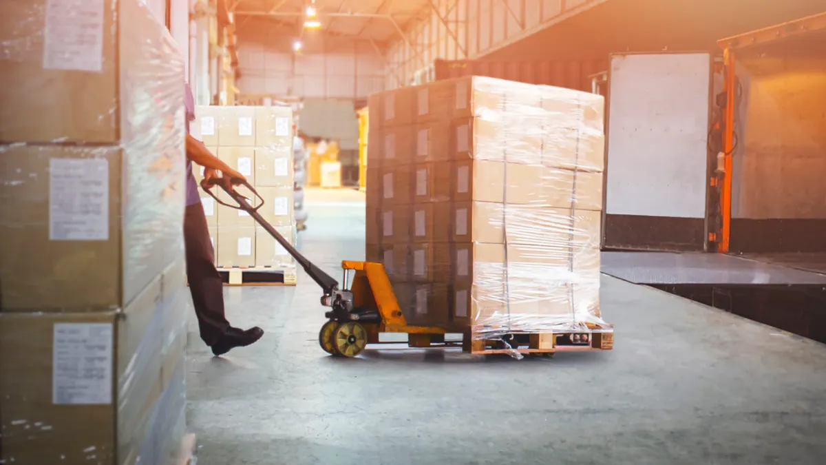 Workers Unloading Packaging Boxes on Pallets in Warehouse