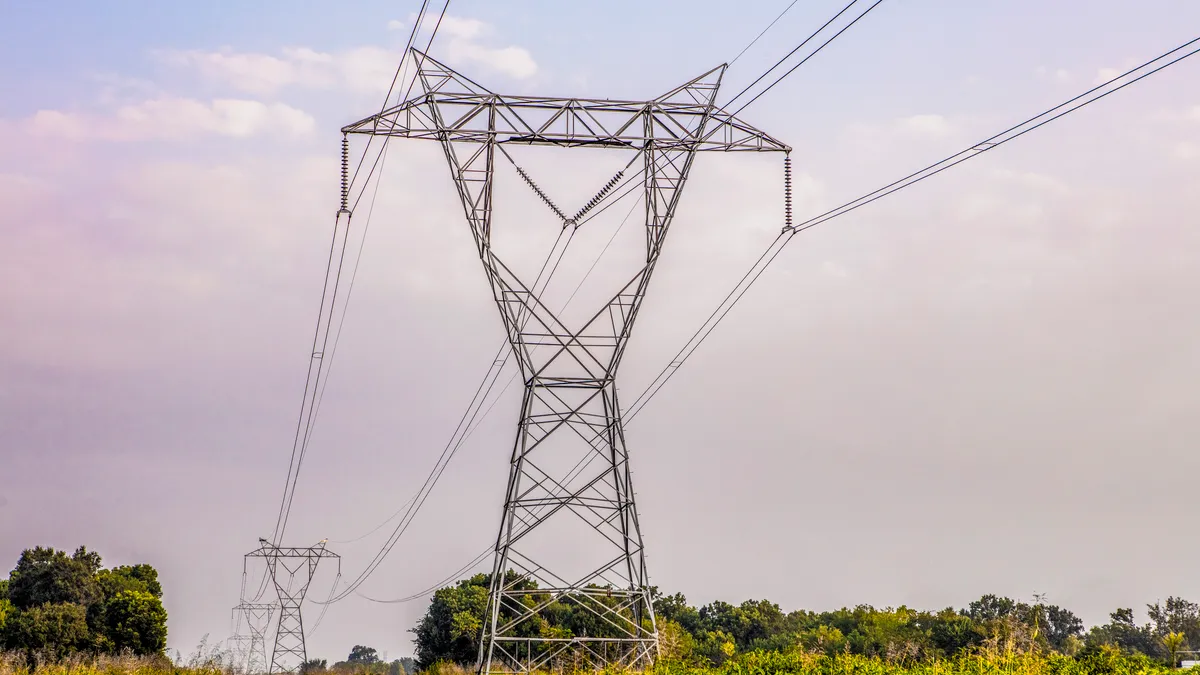 Power line towers crossing a scrubby field.