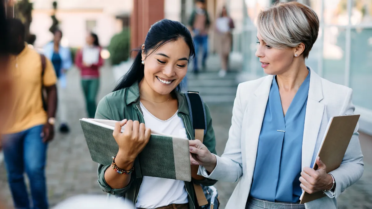 An instructor pointing in a student's book and the student smiling