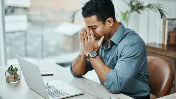 A young businessperson looking stressed while working in a modern office