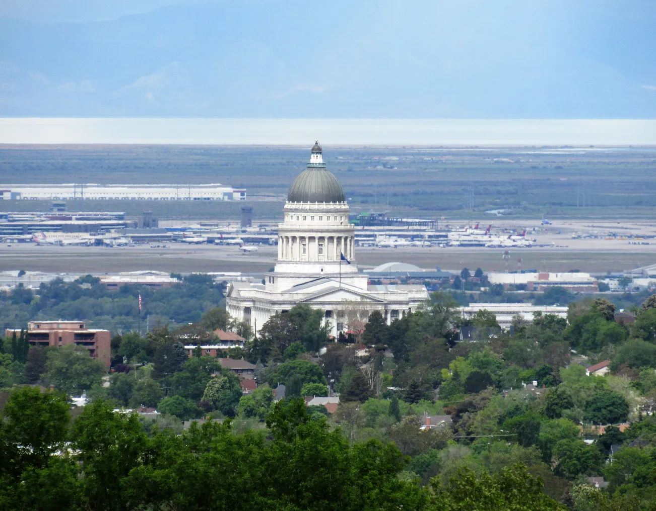 A sky-high view of a large, white domed government building with an airport in the background.