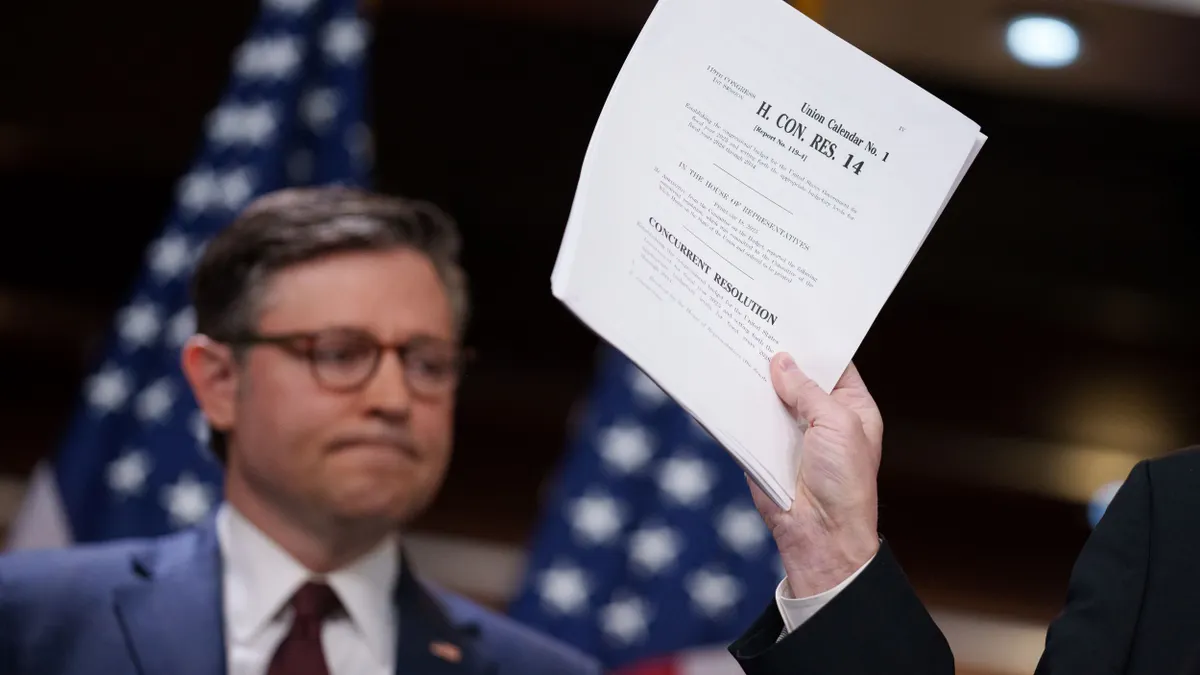 A lawmaker holds up a copy of the 2025 budget resolution