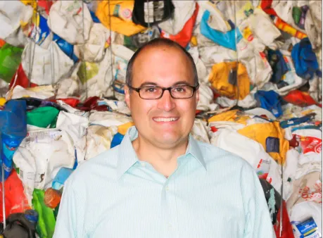 A person standing in front of a bale of plastics