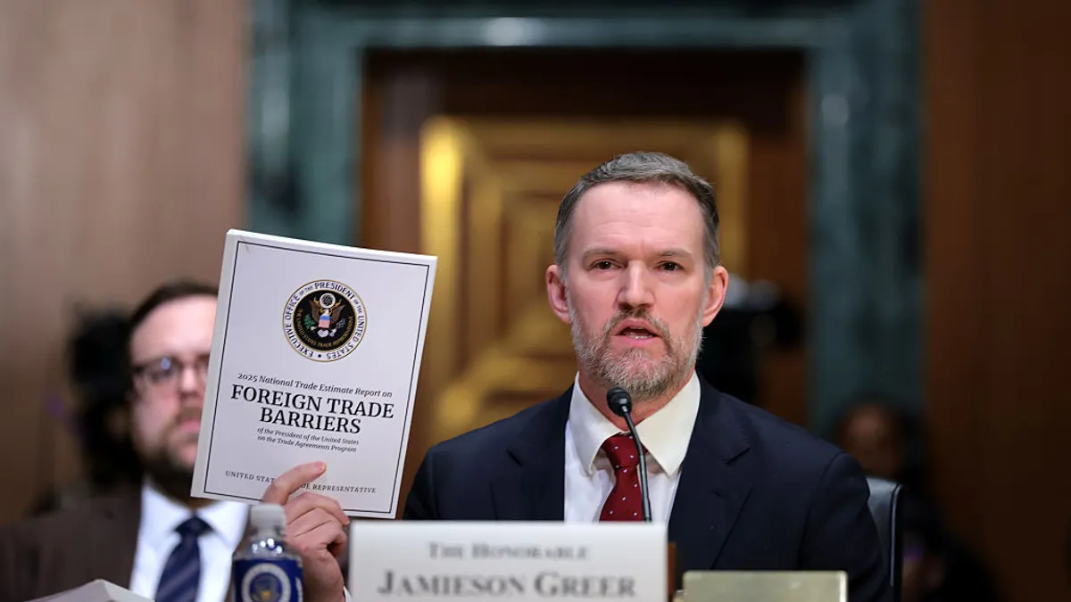 U.S. Trade Representative Jamieson Greer holds up a document that says "foreign trade barriers."