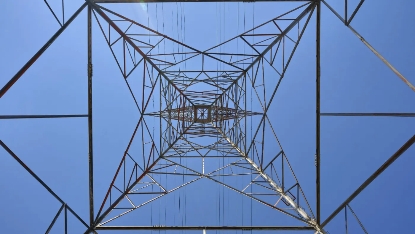 Transmission tower view from below looking straight up against the blue sky.