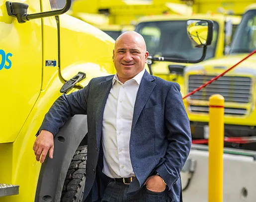 A person in a suit jacket leaning on a waste truck